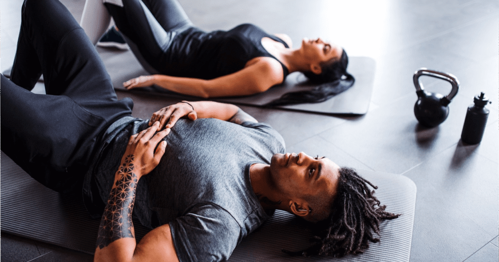 Fit man and a woman are laying on training matts