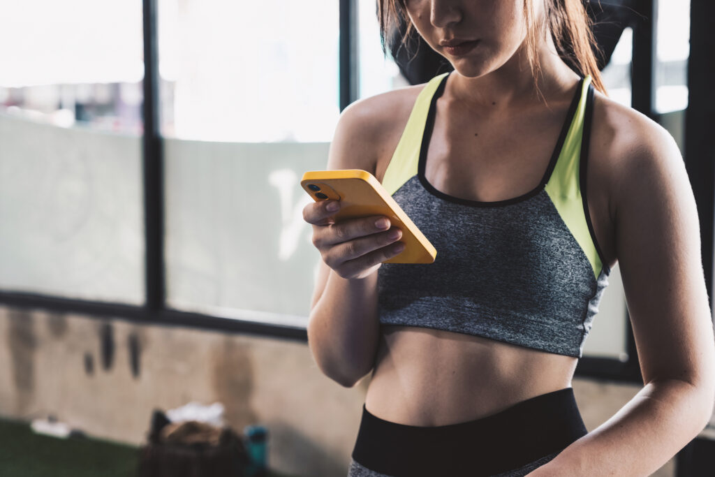 A fit woman looking at her phone in a gym
